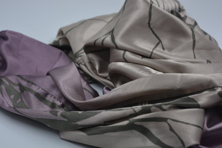 Silk fabric of different colors on a light background. studio photo Beige, sand, delicate purple, thin synthetic, silk fabric with dark lines are on a white.の写真素材