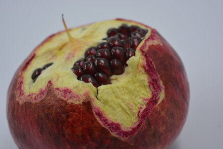 Ripe pomegranate fruit on a white background closeup. One peeled red-orange pomegranate with white,...