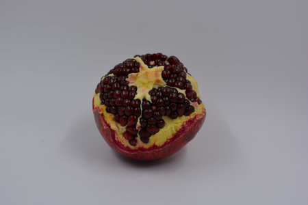 Ripe pomegranate on a white background. Close-up. One peeled red-orange pomegranate with white,...