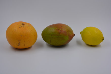 Mango, lemon and grapefruit isolated on a white background. One green-red mango, one yellow lemon, one red-orange grapefruit set on a white matte background.の写真素材