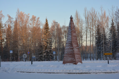 Decorated Christmas tree on the background of the winter forest. The monument of a New Year's tree, a Christmas tree made of wooden sticks, is made in an unusual and unique way.の写真素材