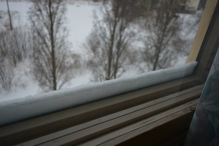 Snow on the windowsill in winter. view from the window. A wooden window made of natural wood.の写真素材