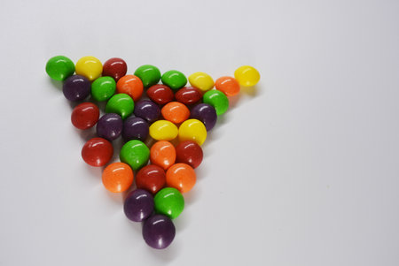 Colorful candies in the shape of a heart on white background. Beautiful, bright chewing and chocolate candies covered with sugar-colored enamel are located on a white plastic.の写真素材