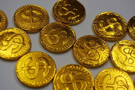 Golden dollar coins on white background, closeup of photo. Beautiful, large gold coins, cents with a dollar $ sign are located on a white plastic background.の写真素材