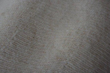 Close up of white woolen fabric texture for background. Selective focus. Things and objects, fabrics and fibers. Soft woolen fabric with fine weave and fine hairs.の写真素材