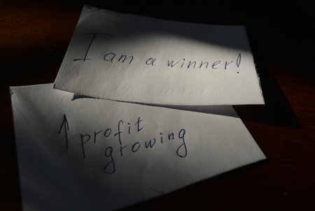 A message from a loved one on a white sheet of paper. Small white pieces of paper with blue ink lettering are arranged on a brown wooden background.の写真素材