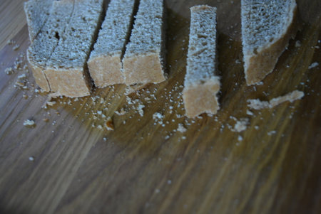 Slices of bread on a wooden cutting board. Selective focus. Croutons of different shapes are arranged on a brown wooden board made of natural wood.の写真素材