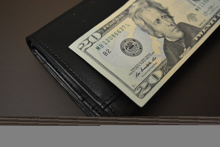 Black leather wallet with one hundred dollar banknote. Black women's wallet made of genuine leather,...