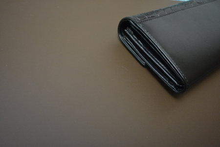 Black leather wallet on a gray background, closeup of photo. Beautiful black women's wallet made of...