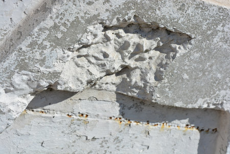 Close-up of a concrete wall with a hole in it. Construction materials, repair work, broken reinforced concrete cement fence, block, paving slabs.の写真素材