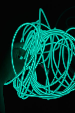 Close-up of electric cable in neon light. Abstract background. Neon chaotic lines are arranged in...