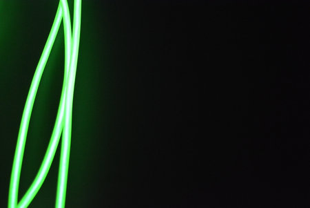 Green neon lines on a black background, close-up of photo. Neon chaotic lines are arranged in spirals, circles, twists are arranged on a black background.の写真素材