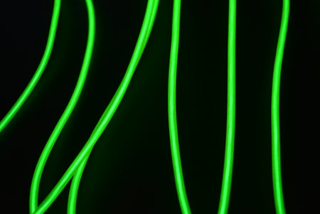 Green neon lines on a black background. Abstract background for design. Neon chaotic lines are arranged in spirals, circles, twists are arranged on a black background.の写真素材