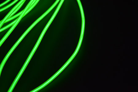 Green neon lines on a black background, abstract background for design. Neon chaotic lines are arranged in spirals, circles, twists are arranged on a black background.の写真素材