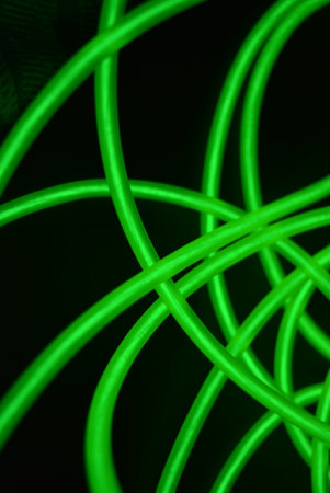 Green neon wire on a black background, close-up of photo. Neon chaotic lines are arranged in spirals, circles, twists are arranged on a black background.の写真素材