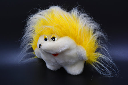 Beautiful and bright things, children's soft toys. A large white-soft yellow hedgehog is located on a black plastic background.の写真素材