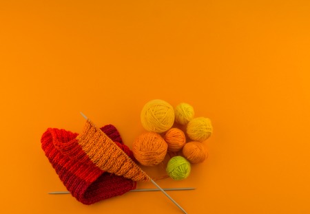 Rainbow cap made of wool on an orange background. Copy space. View from above. Striped knitted warm hat with pompon.の写真素材