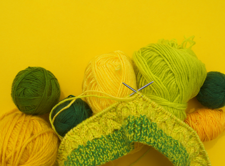 Yellow and green coats of wool lie on the table. Favorite hobby is knitting. Home cosiness.の写真素材