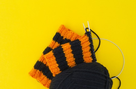 The process of knitting gaiters on a Halloween holiday. Witch costume. Autumn cosiness. Yellow background.の写真素材
