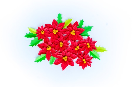 Paper flower poinsettia and leaves of holly. Christmas wreath. White background. Colors are green, red, yellow.の写真素材