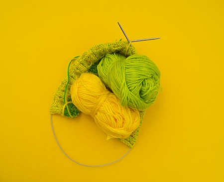 Yellow and green coats of wool lie on the table. Favorite hobby is knitting. Home cosiness.の写真素材