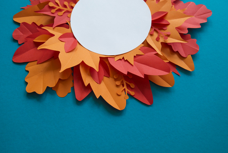 Leaves of paper autumn in a circle. Red, yellow and orange leaves. Place for recording. Blue background.の写真素材