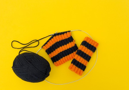 The process of knitting gaiters on a Halloween holiday. Witch costume. Autumn cosiness. Yellow...