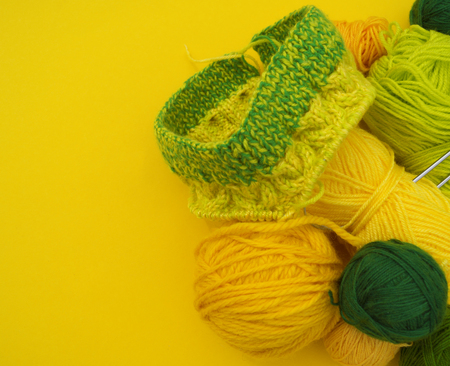 Yellow and green coats of wool lie on the table. Favorite hobby is knitting. Home cosiness.の写真素材