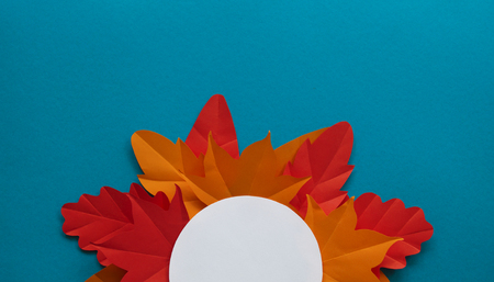 Leaves of paper autumn in a circle. Red, yellow and orange leaves. Place for recording. Blue background.の写真素材