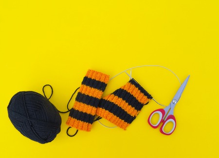 The process of knitting gaiters on a Halloween holiday. Witch costume. Autumn cosiness. Yellow background.の写真素材