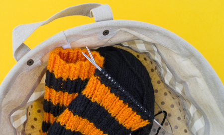 The process of knitting gaiters on a Halloween holiday. Witch costume. Autumn cosiness. Yellow background.の写真素材