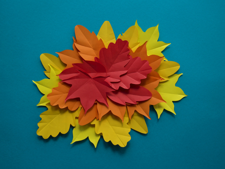 Leaves of paper autumn in a circle. Red, yellow and orange leaves. Place for recording. Blue background.の写真素材