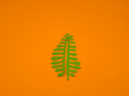 Green leaves made from paper on orange background. Autumn leaf fall. Favorite hobby handicraft.の写真素材