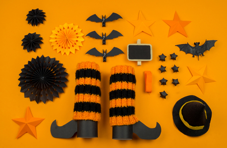 Orange background with collection of Halloween objects overhead view. Black cat, spider, bat, witch, feared party decor. Handwork.の写真素材