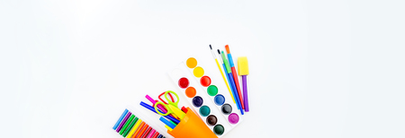Pencils and felt-tip pens in a plastic cup, paints and pastel crayons on a white background. Back to school. Scissors and tools for the student. Tipped over.の写真素材