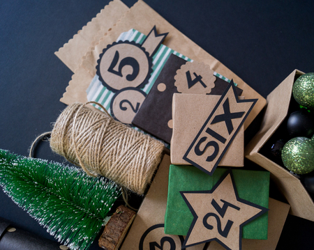 Advent calendar with gift bags and boxes filled with candy. Christmas decor. Gift wrapping Kraft paper. Black background.の写真素材