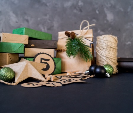 Advent calendar with gift bags and boxes filled with candy. Christmas decor. Gift wrapping Kraft paper. Black background.の写真素材