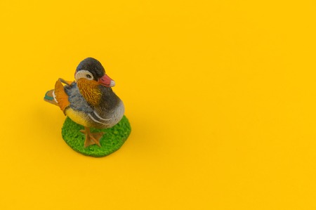 Toy mandarin duck from plastic on a yellow background. African animal for a child. Place to write.