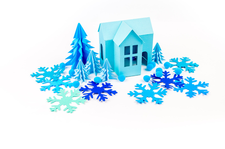 Blue house glued out of paper stands in the Violet forest. White background. Children's crafts. Christmas tree. Snowballs and Snowflakeの写真素材