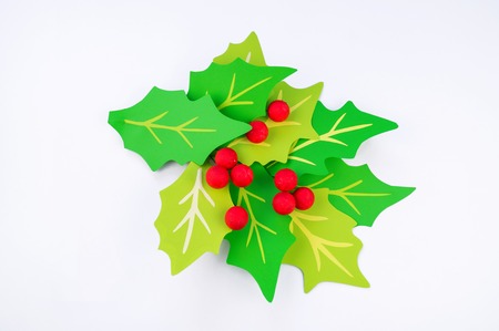 Flower holly made of paper crafts. Red berry from the ball. Christmas leaves. White background. Children's creativity.の写真素材