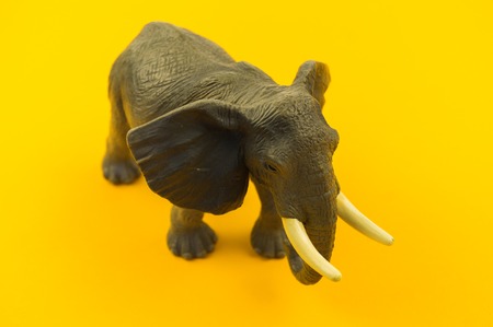 large plastic elephant toy on a yellow background. African animal for a child. Copy space.の写真素材