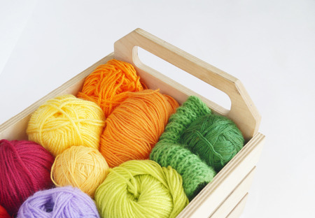 Colorful woolen balls of yarn are in the basket. Needlework. Knitting. Threads of red,orange,yellow,...