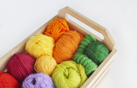 Colorful woolen balls of yarn are in the basket. Needlework. Knitting. Threads of red,orange,yellow, green and blue colors.の写真素材
