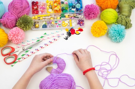 The child is engaged in a favorite hobby. The kid makes a pom-pom from a woolen thread monster. Holiday toy gift. Creativity with children. School kindergarten. Material for crafts.の写真素材