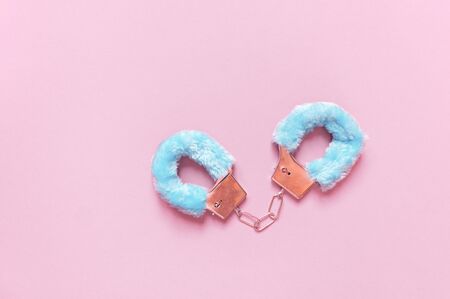 Handcuffs with blue hair adult sex toys, minimal design, isolated on a pink background. Bdsm in the bed. The role of dominantsの写真素材