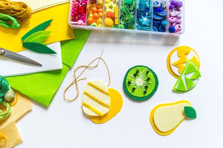 Felt stitched fruit. Material and tools for creativity on a white background. Sewing toys for a...