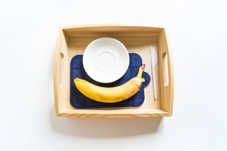 Montessori cooking material in the kitchen. Child's hand peels and cuts a banana. Breakfast.の写真素材