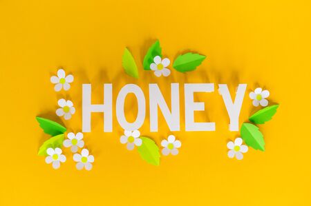 Holiday honey. Yellow background. Handicraft bee painted egg. Easter Origami paper flower. Lettering.の写真素材