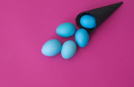 The eggs roll out of the black horn. Pink background. Bright holiday easter. Concept