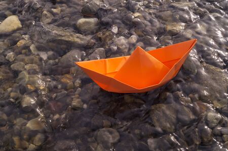 A boat made of colored paper in the snow. Origami handicraft. Spring the river is melting. Bright colorの写真素材
